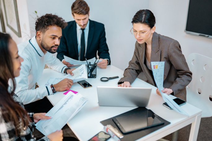 Business People Sitting at White Table Looking at Laptop